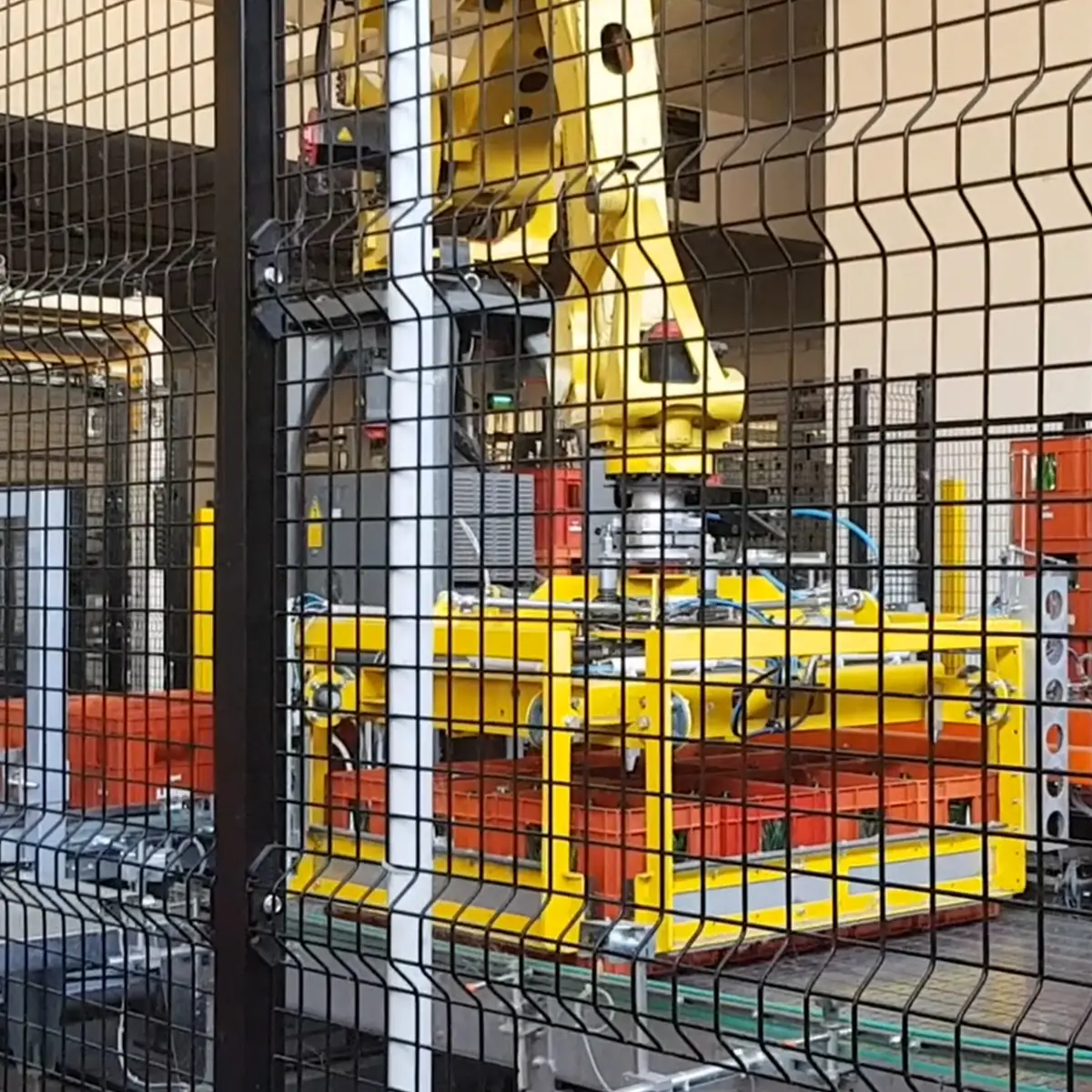 Braccio del depallettizzatore 'PANTHER' in fase operativa, sollevando casse di contenitori arancioni all'interno di un'area di lavoro protetta.