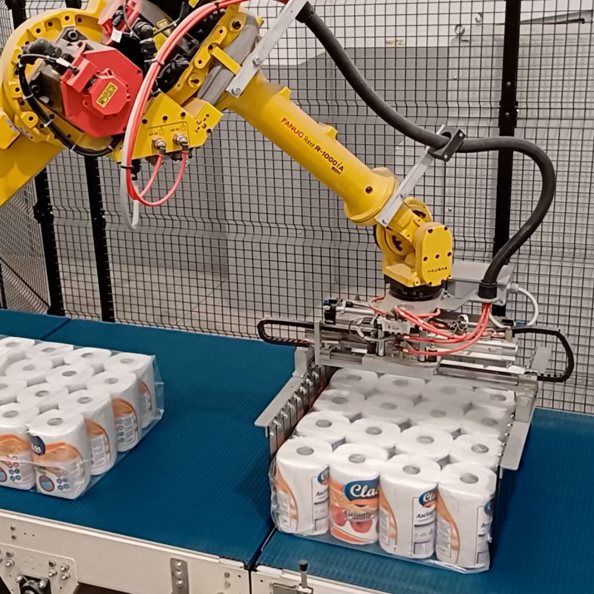 braccio robotico che prepara rotoli di carta per il posizionamento per la presa a strato del pallettizzatore