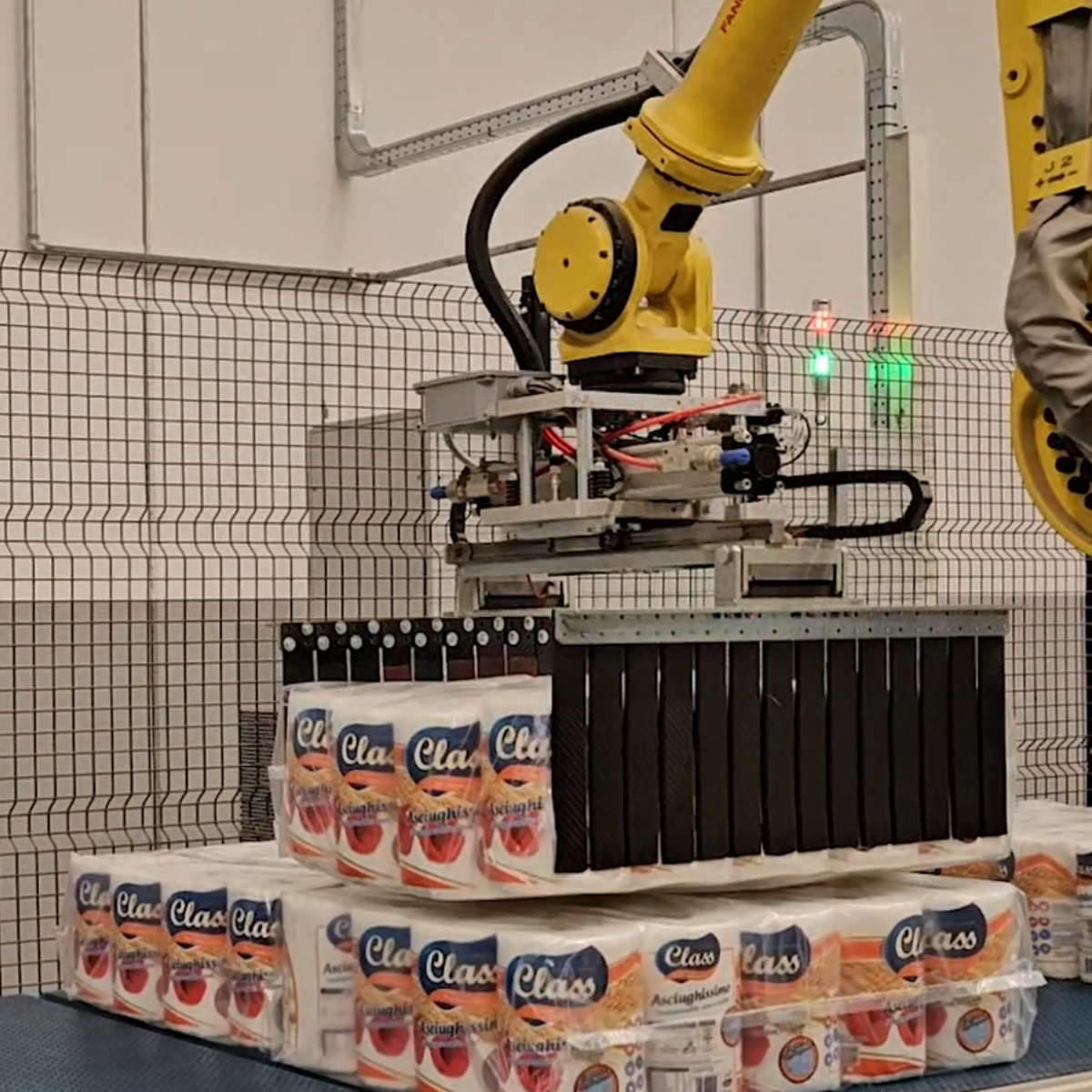 braccio robotico che prepara rotoli di carta per il posizionamento per la presa a strato del pallettizzatore