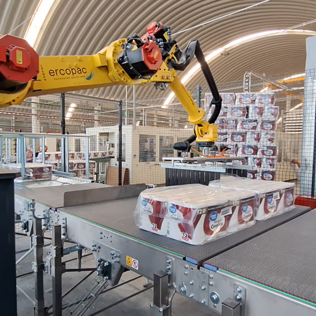 braccio robotico antropomorfo che manipola rotoli di carta su un nastro trasportatore per la preparazione dello strato in una fabbrica tessile