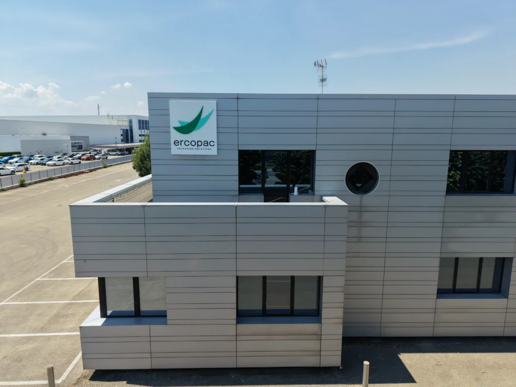 Facciata dell'edificio uffici Ercopac a Fiorano Modenese con logo aziendale in primo piano, rivestimento in pannelli grigi e cielo azzurro