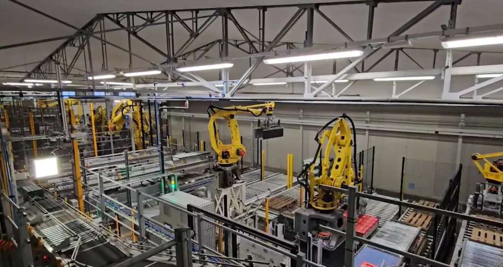 Fine linea completamente robotizzato Ercopac con robot Fanuc gialli su più livelli, nastri trasportatori e sistemi di pallettizzazione automatica, installazione identificata come la più robotizzata d'Europa