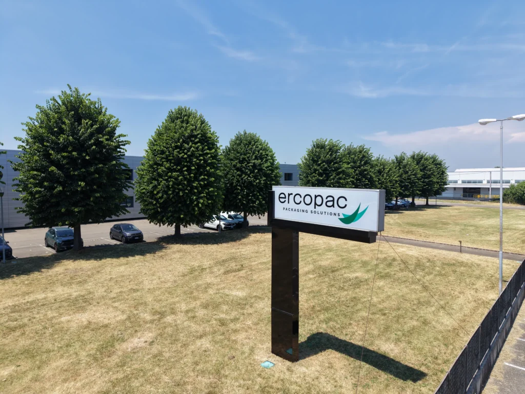 Aerial view of the corner of the Ercopac industrial warehouse in Fiorano Modenese: a two-story office building featuring the company logo, the roof of the production area with solar panels, and an outdoor parking lot