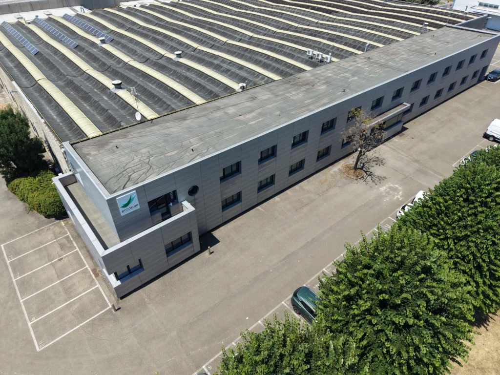 Vista aerea della nuova sede Ercopac a Fiorano Modenese: edificio uffici su due piani con logo aziendale, capannone produttivo con pannelli solari sul tetto e parcheggio esterno
