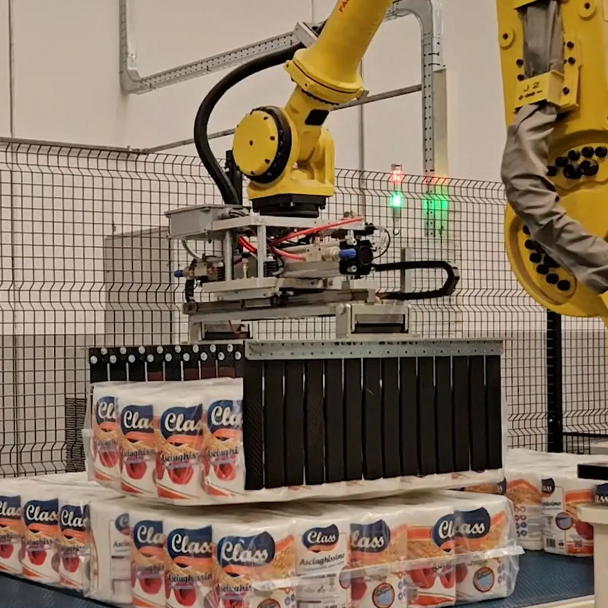 Robot antropomorfo per preparazione a strato mentre manipola confezioni di rotoli di carta in una linea di produzione, evidenziando la precisione e la capacità di movimentazione del robot.