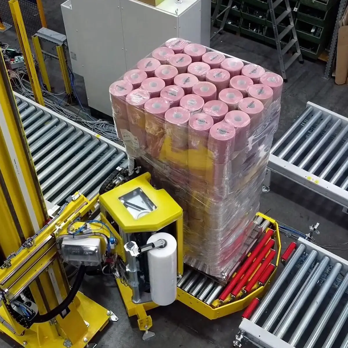 Vista dall'alto di un pallet avvolto da SPIDER-S con rotoli rosa, mostrando la precisione della fasciatura su una linea automatizzata.