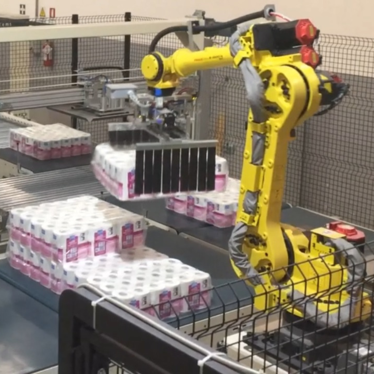 braccio robotico che prepara rotoli di carta per il posizionamento per la presa a strato del pallettizzatore