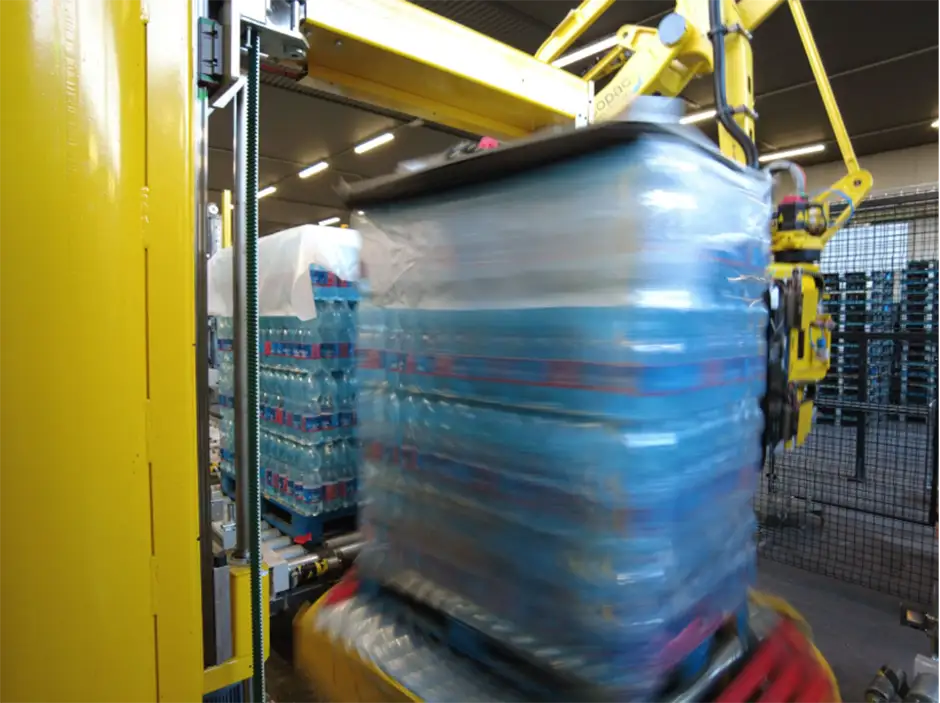 Sistema di fasciatura robotizzato in azione su un pallet di bottiglie d’acqua, con avvolgimento ad alta velocità tramite film plastico in un impianto automatizzato Ercopac.