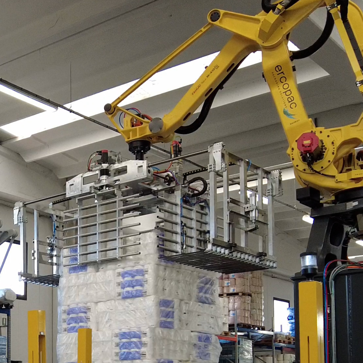 pallettizzatore robotizzato a strato con la pinza aperta durante la presa di uno strato di prodotto cartario